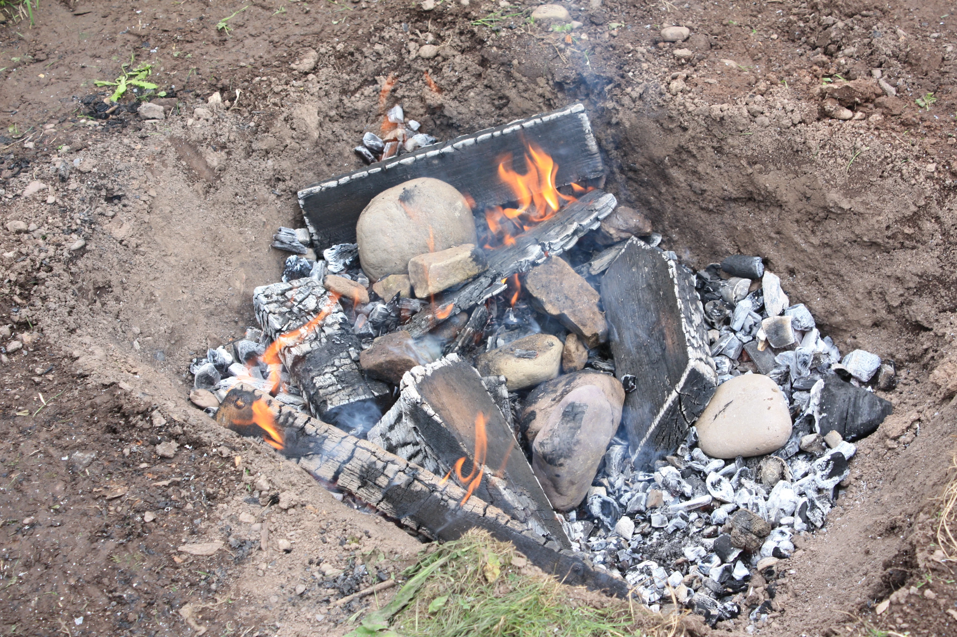 Stage 3: Once the flames have died down, add stone to the charcoal