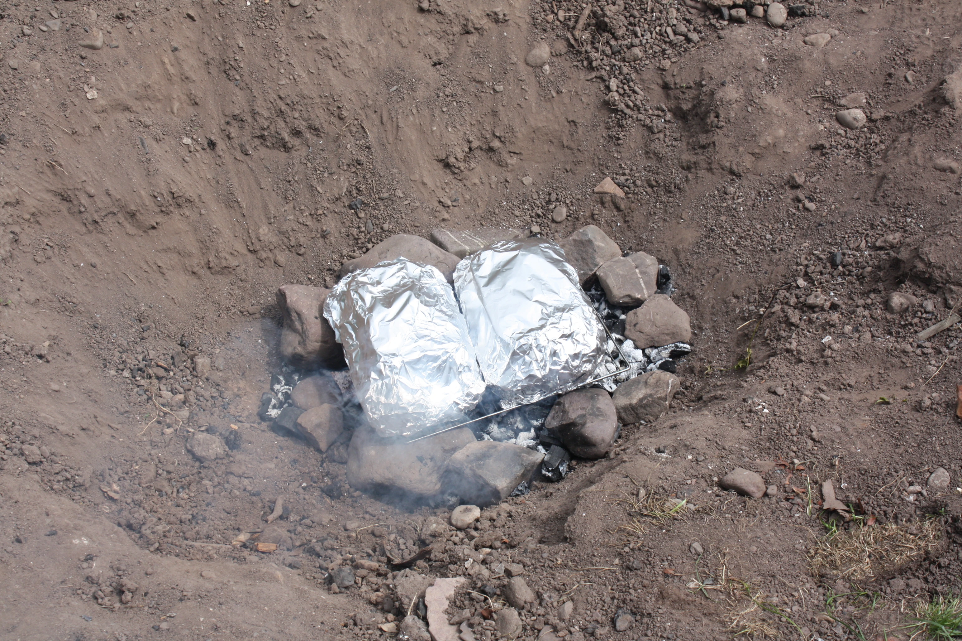 The meat is added to the fire and surrounded with hot rocks